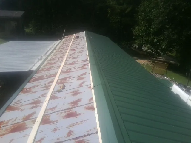 Old rusted panels beside newly installed green metal roofing — Wind Damage Roof Repair by Roofing Brothers in Dietrich