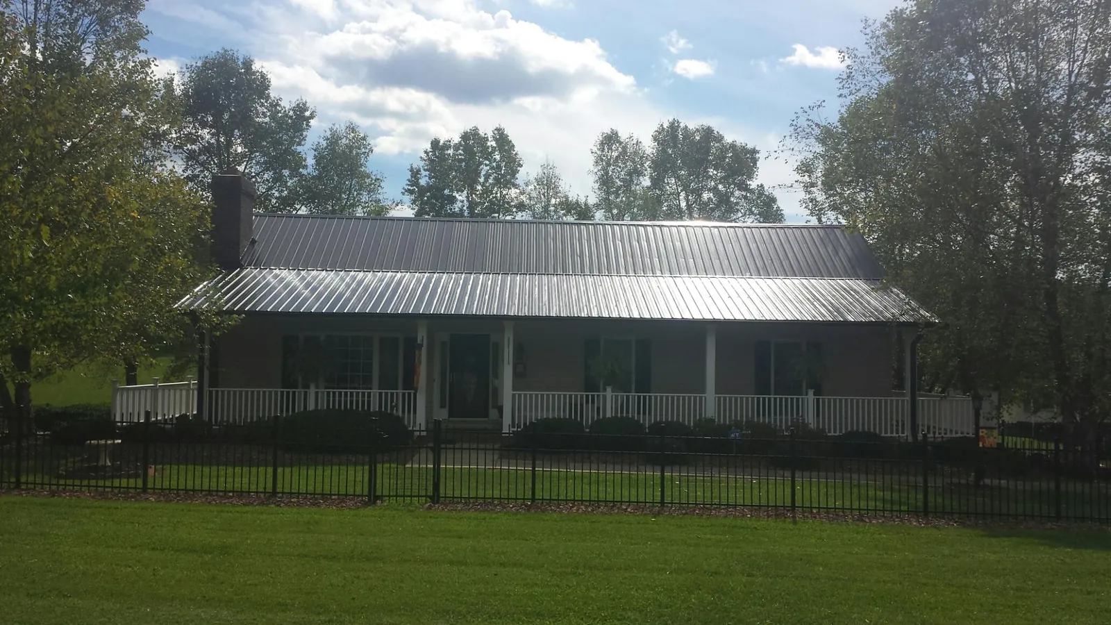 Gray metal roof on a brick ranch with a full width front porch — Gutter Guard Installation work by our crew in Dietrich