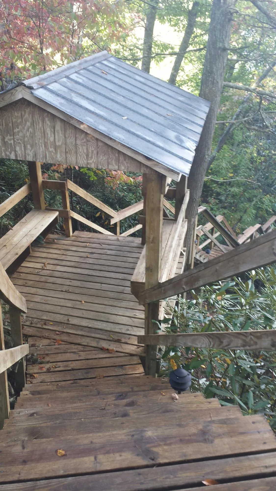 Metal roofed shelter over wooden steps on a wooded walkway — Skylight Repair & Installation work by our crew in Dietrich