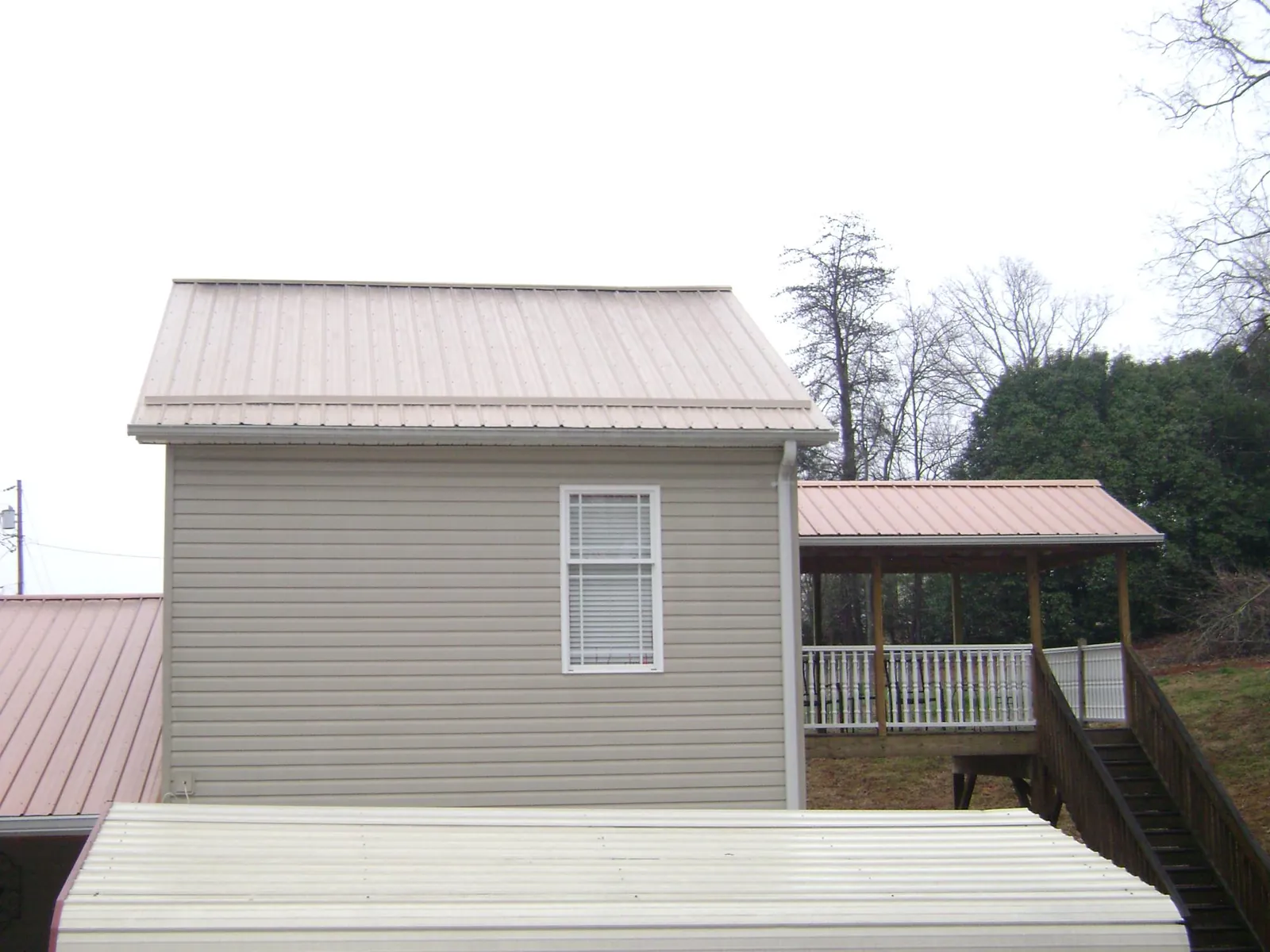 Tan metal roofs on a two story addition and attached porch, from a Roof Replacement job in Dietrich