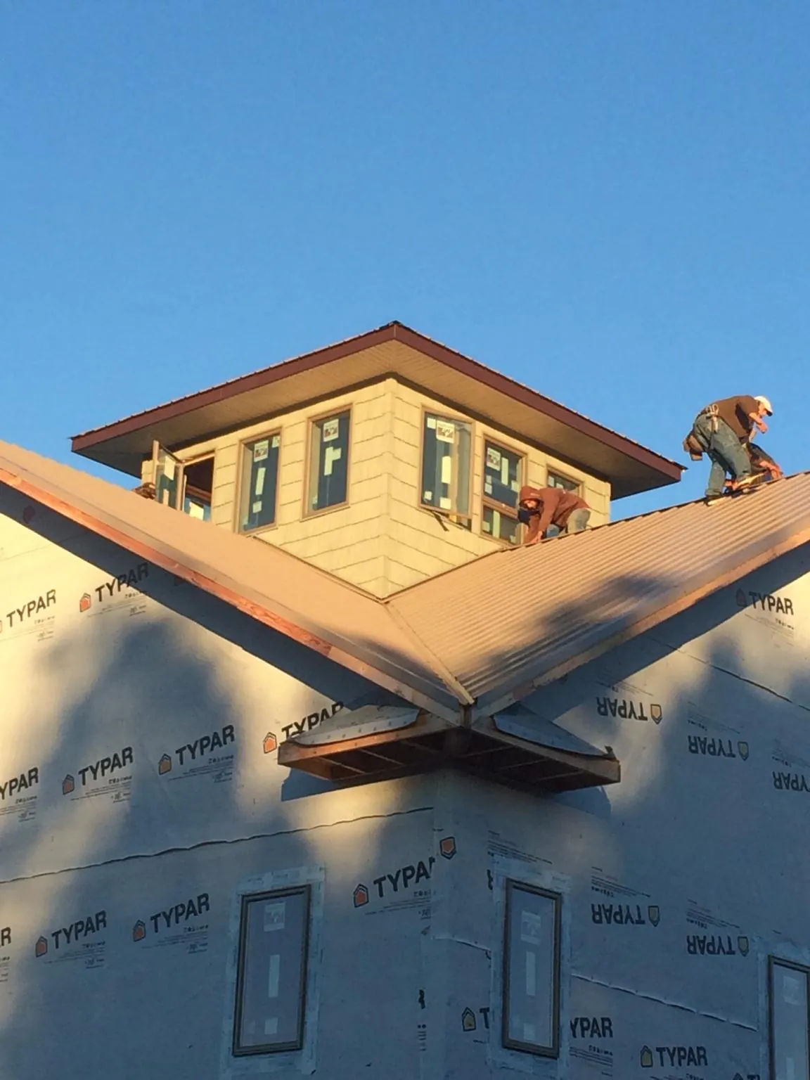 Roofers working around a rooftop cupola on a new metal roof at sunset — Roof Waterproofing in Dietrich by Roofing Brothers